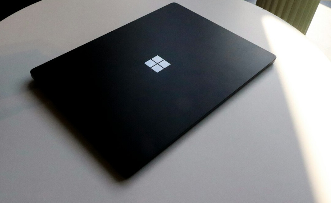 Hand writing notes next to a laptop on a wooden desk